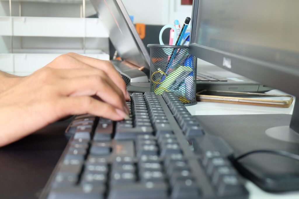 les mains d'une femme tapent sur un clavier d'ordinateur
